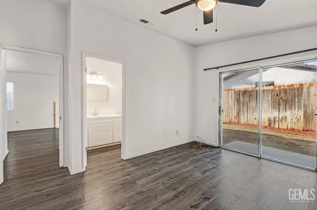an empty room with wooden floor fan and windows