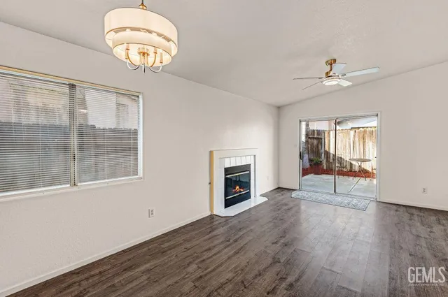 an empty room with wooden floor chandelier fan and windows