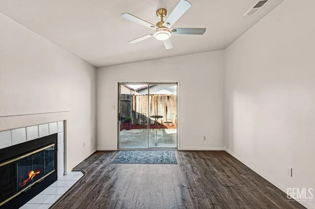 a view of a livingroom with a fireplace a ceiling fan and wooden floor