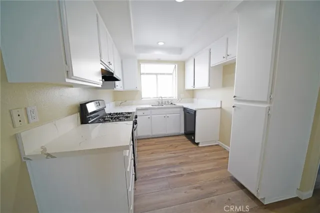 a kitchen with a sink a stove top oven and white cabinets
