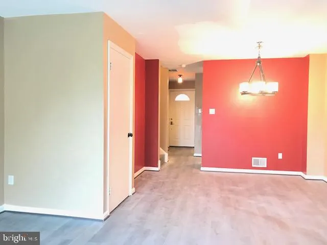 an empty room with a kitchen space and a hallway