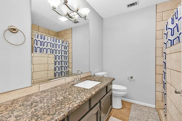 a bathroom with a granite countertop sink a toilet and mirror