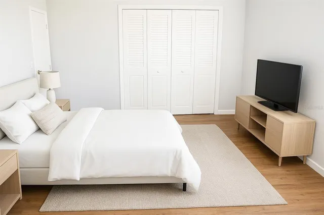 a spacious bedroom with a bed and a flat screen tv