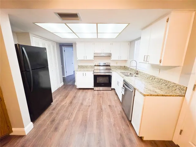 a kitchen with a refrigerator a sink and wooden floor