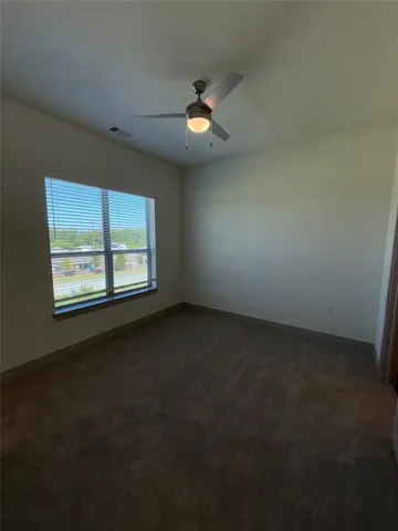 an empty room with windows and fan