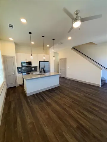 a large kitchen with stainless steel appliances a large counter top a sink a refrigerator and a fireplace