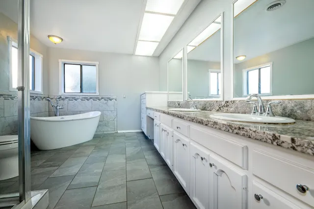 a bathroom with a granite countertop toilet a sink and mirror