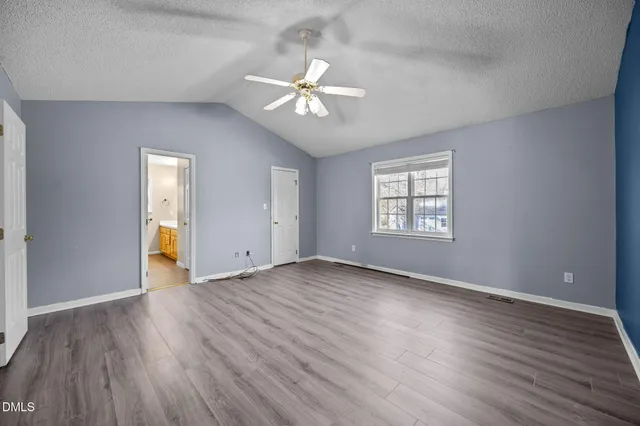 an empty room with wooden floor chandelier fan and windows