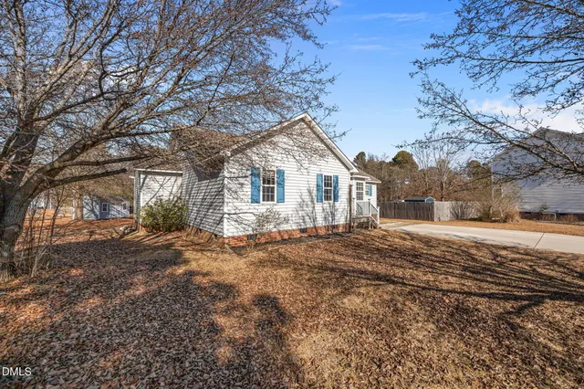 a view of house with yard and trees in the background