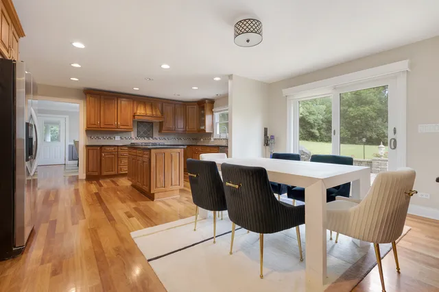 a kitchen with stainless steel appliances kitchen island granite countertop a refrigerator a sink a stove a dining table and chairs