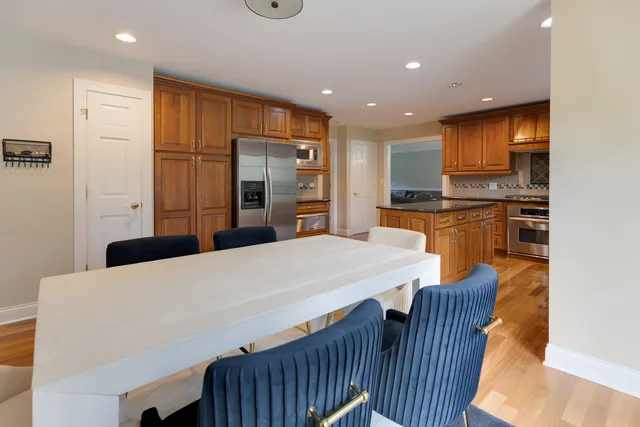 a kitchen with granite countertop a stove a sink a dining table and chairs