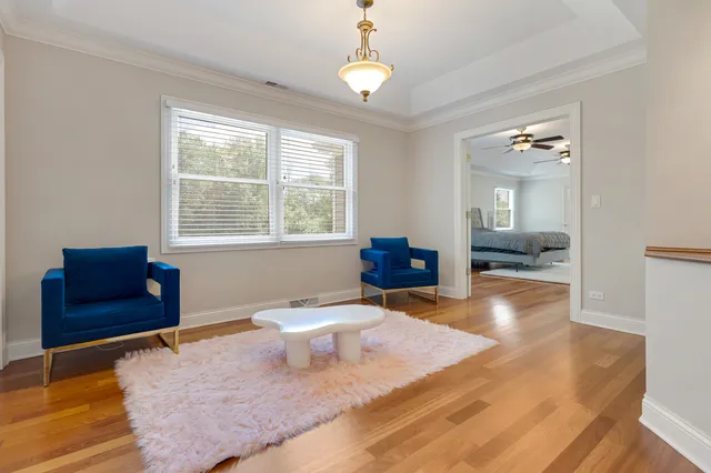 a living room with a bed furniture chandelier and a window