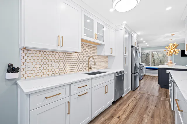 a kitchen with a sink dishwasher and white cabinets with wooden floor
