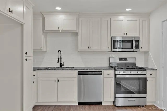 a kitchen with granite countertop white cabinets and stainless steel appliances