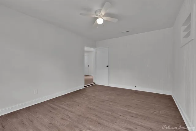 an empty room with wooden floor and fan
