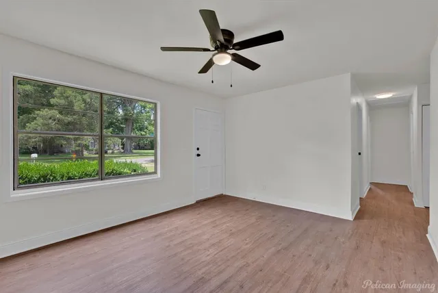 a view of an empty room with wooden floor and a window