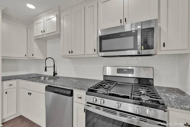 a kitchen with granite countertop a stove and a microwave