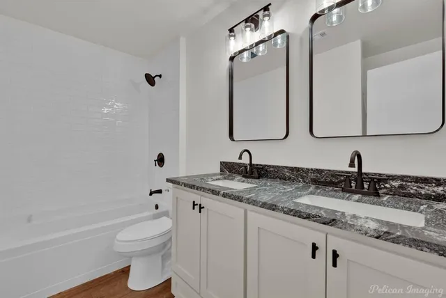 a bathroom with a granite countertop sink a toilet and a bathtub