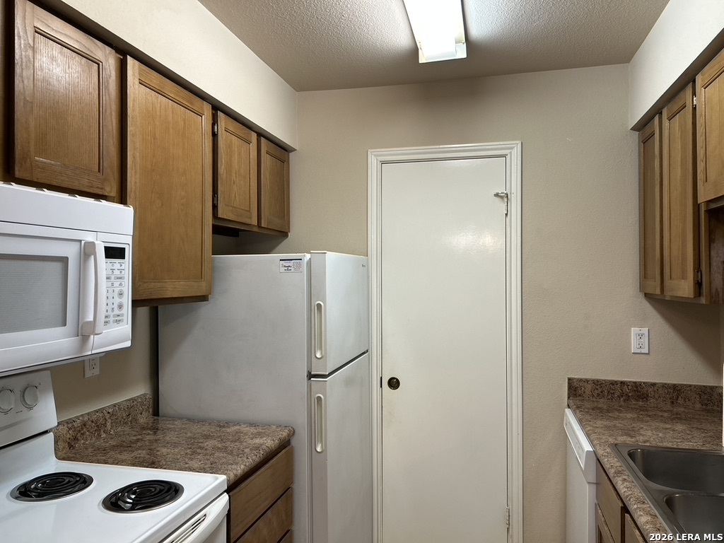 13018 Heimer Road, Unit 710 San Antonio, TX 78216 - Photo 9 of 27 a kitchen with a stove a refrigerator and cabinets