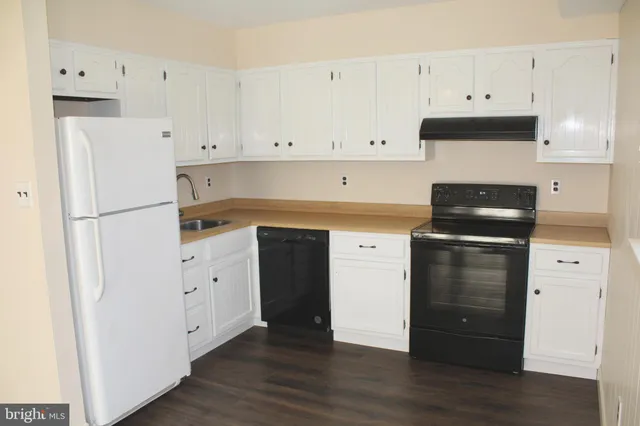 a kitchen with granite countertop white cabinets and refrigerator