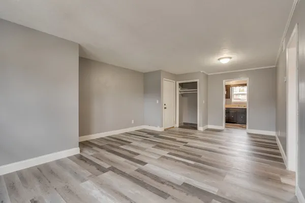 a view of an empty room with window and wooden floor