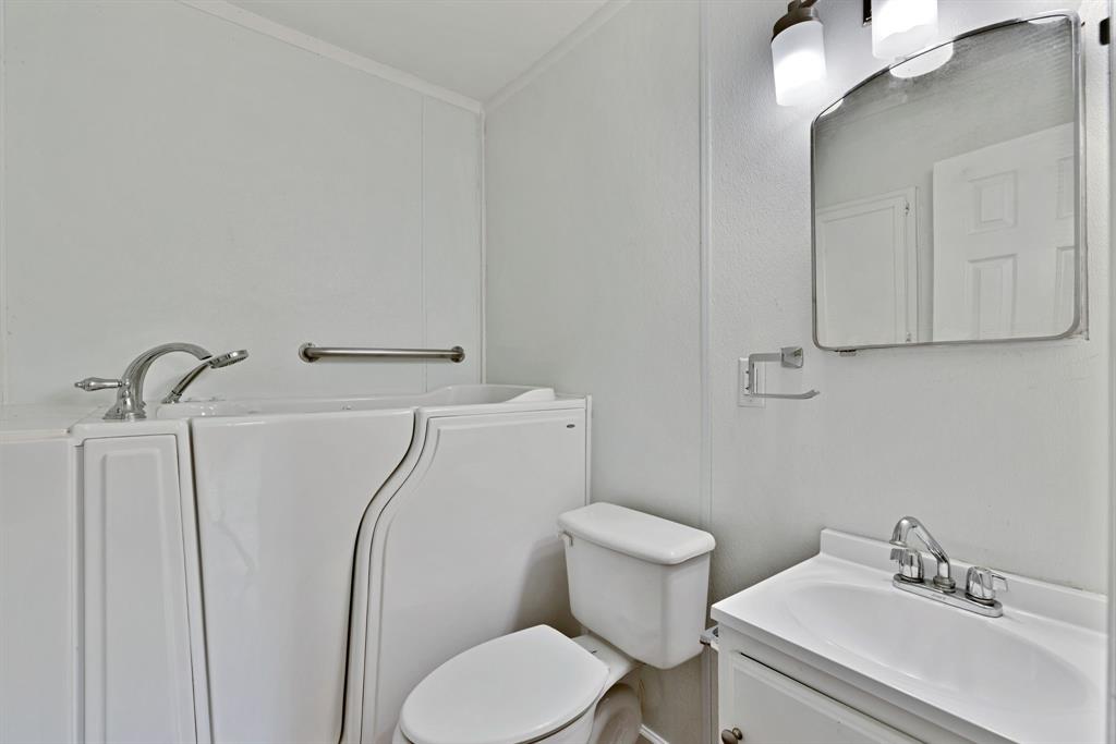 613 Cheyenne Road Dallas, TX 75217 - Photo 13 of 28 Bathroom featuring a white walk-in bathtub with chrome fixtures, a white toilet, and a vanity with an integrated sink and chrome faucet