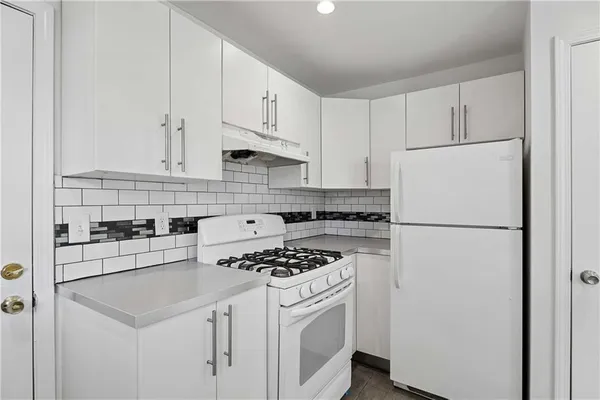 a white refrigerator freezer sitting inside of a kitchen with white cabinets