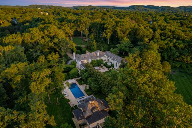 an aerial view of residential house with outdoor space and trees all around