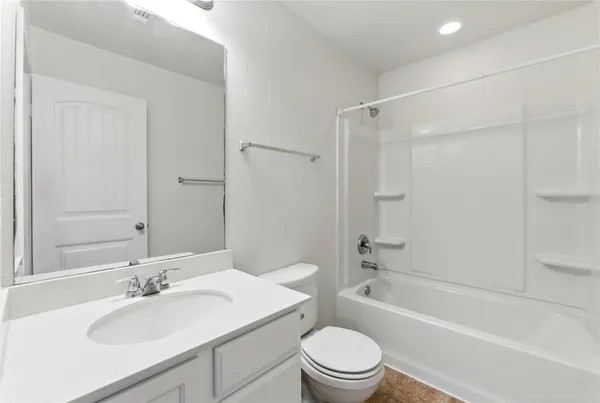 a bathroom with a bathtub shower sink vanity mirror and toilet