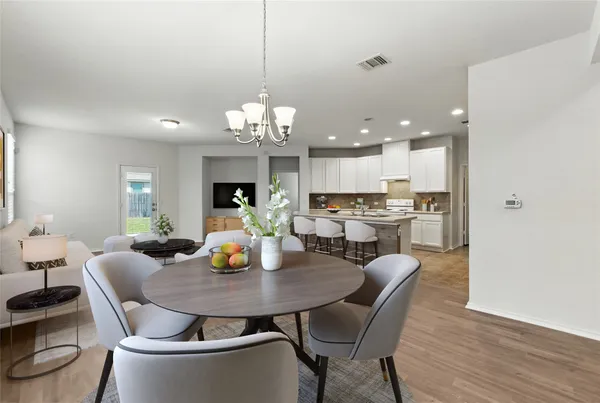 a view of a dining room and livingroom with furniture wooden floor a chandelier