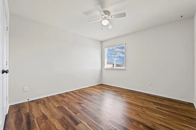 a view of a room with wooden floor and a ceiling fan