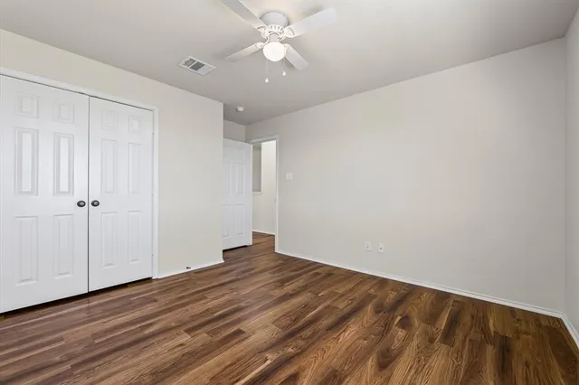 a view of a room with wooden floor and a ceiling fan