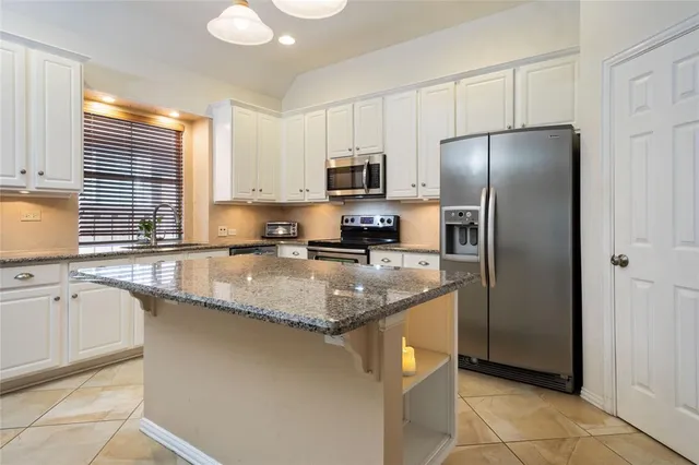 a kitchen with granite countertop white cabinets stainless steel appliances and a sink
