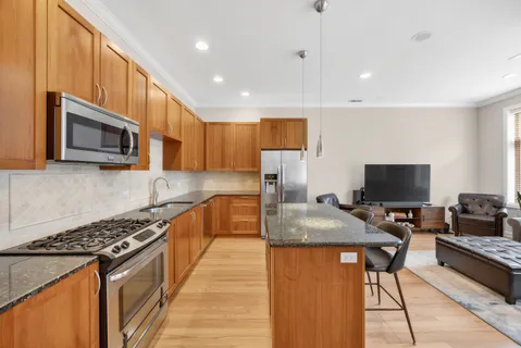 a kitchen with stainless steel appliances granite countertop a stove top oven a sink dishwasher a dining table and chairs with wooden floor