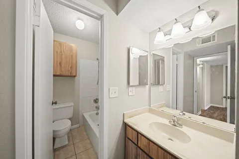 a bathroom with a sink a toilet and shower a mirror