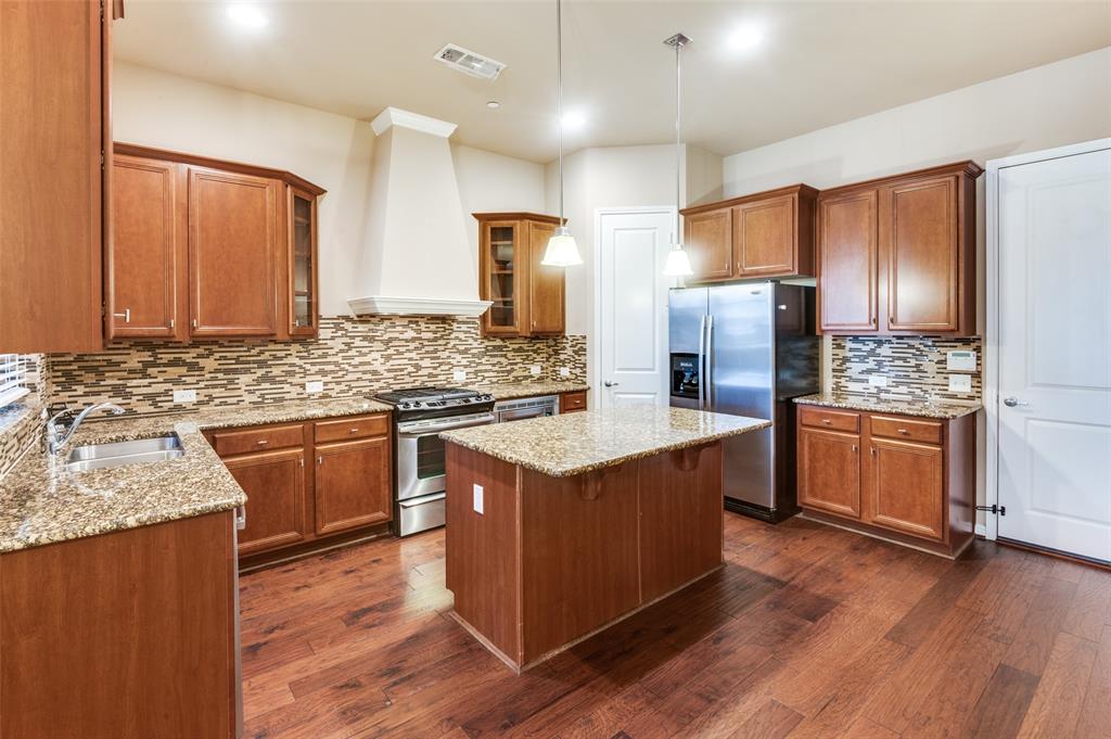 1915 Luther Road Irving, TX 75063 - Photo 8 of 25 a kitchen with stainless steel appliances granite countertop a stove a sink dishwasher a refrigerator and wooden cabinets with wooden floor
