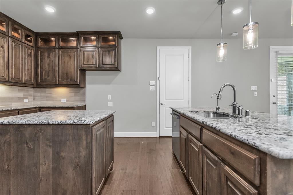 6333 Hall Road Frisco, TX 75034 - Photo 15 of 38 Kitchen featuring two islands, wood-finish flooring, dark wood cabinetry with integrated lighting, and light-toned countertops
