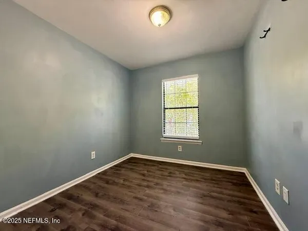 a view of a hallway with wooden floor and a bathroom