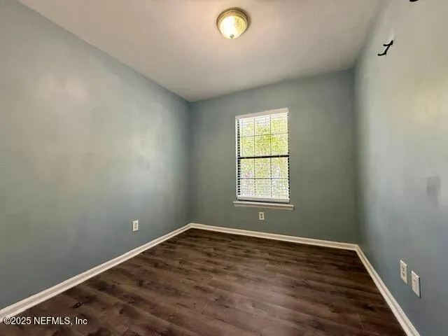 a view of a hallway with wooden floor and a bathroom