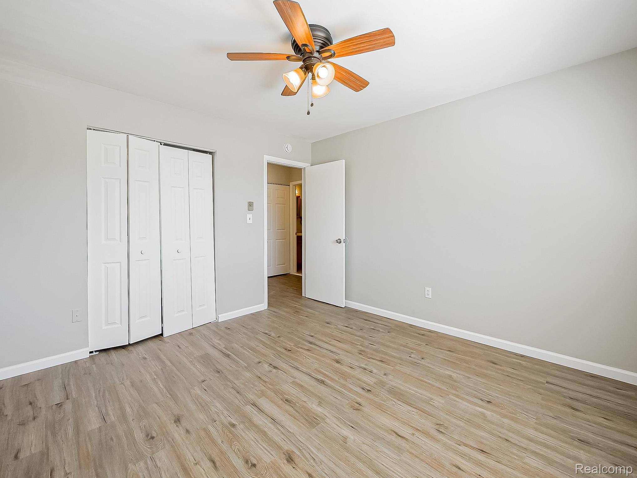 125 East Van Riper Road, Unit 5 Fowlerville, MI 48836 - Photo 18 of 23 Unfurnished bedroom with light wood finished floors, a ceiling fan, and a closet
