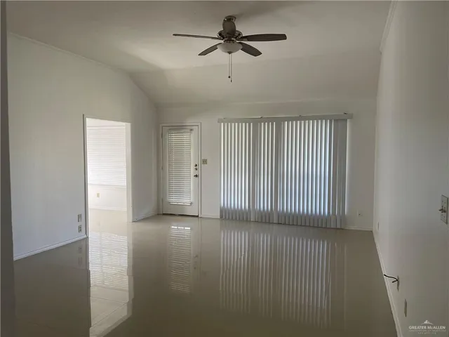 an empty room with windows and fan