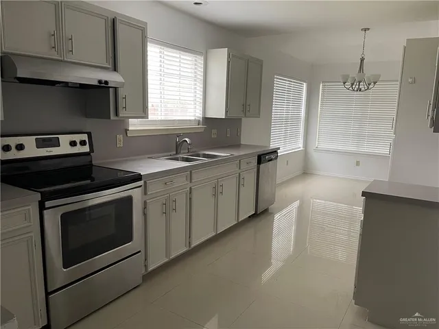 a kitchen with stainless steel appliances a stove a sink and white cabinets