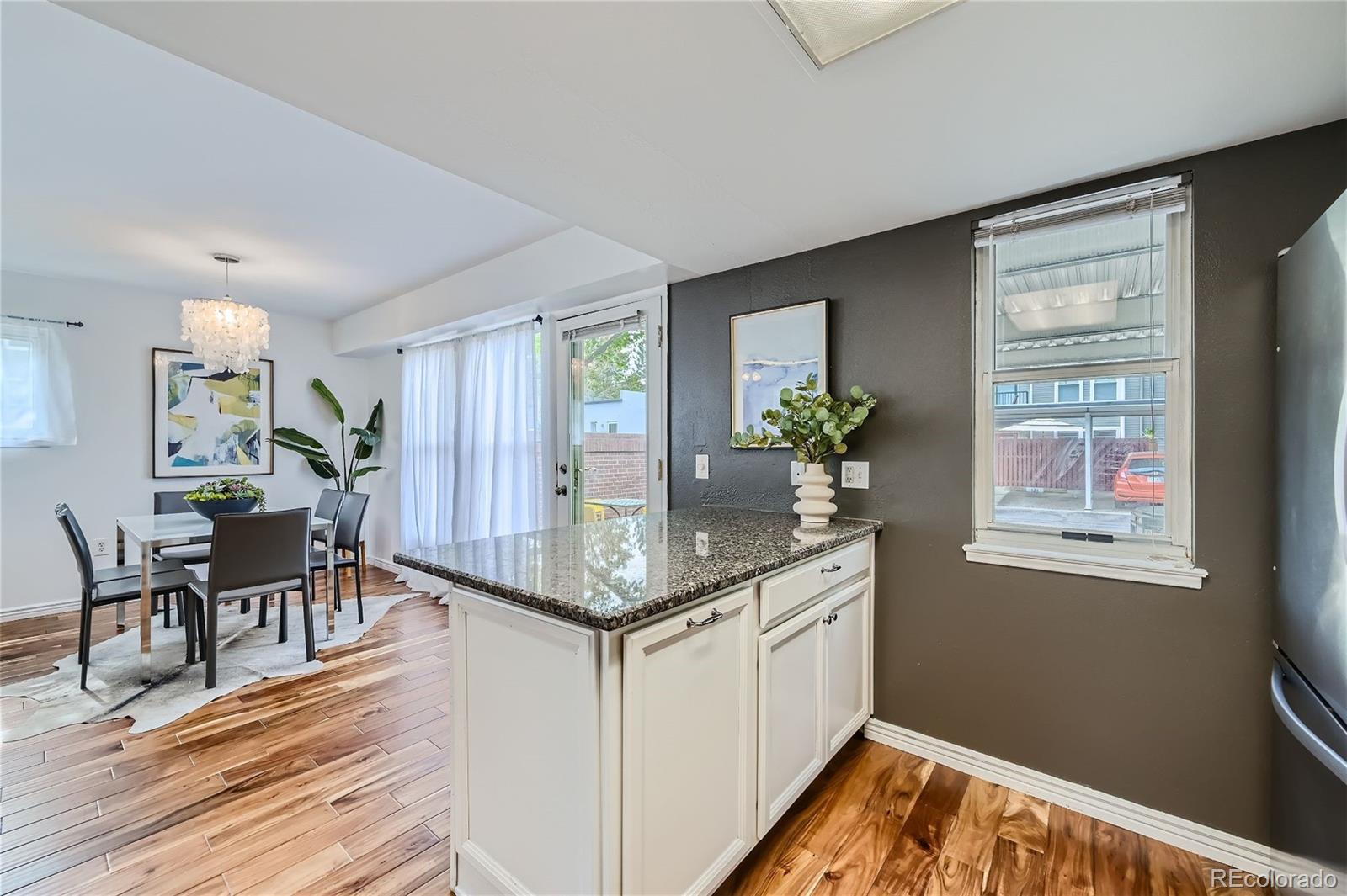 1150 Inca Street, Unit 74 Denver, CO 80204 - Photo 8 of 32 a kitchen with stainless steel appliances granite countertop wooden floor window and dining table