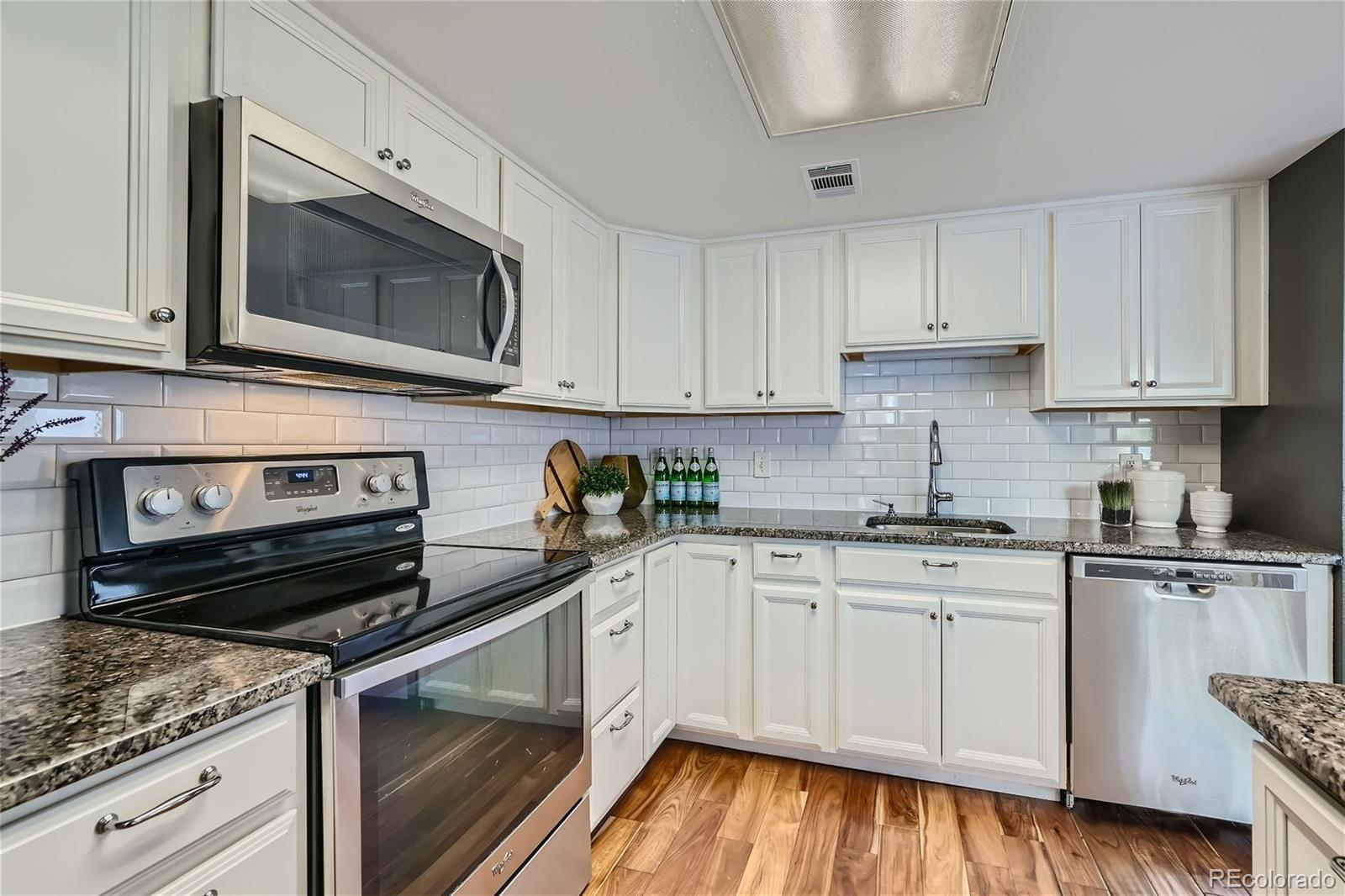 1150 Inca Street, Unit 74 Denver, CO 80204 - Photo 9 of 32 a kitchen with stainless steel appliances granite countertop a stove a microwave and cabinets