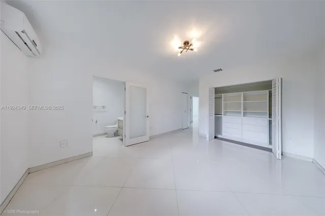 a view of an empty room with closet and a window