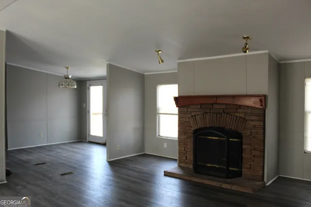 a view of an empty room with wooden floor fireplace and a window