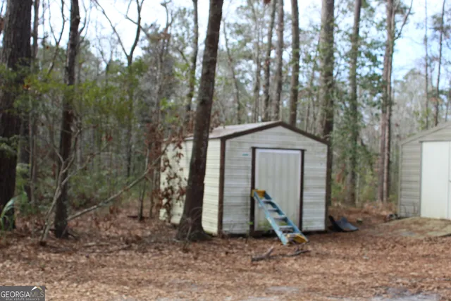 a view of a wooden house with a yard and large trees