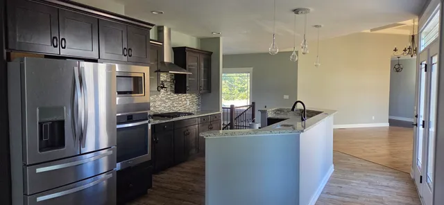 a kitchen with kitchen island granite countertop wooden cabinets and stainless steel appliances