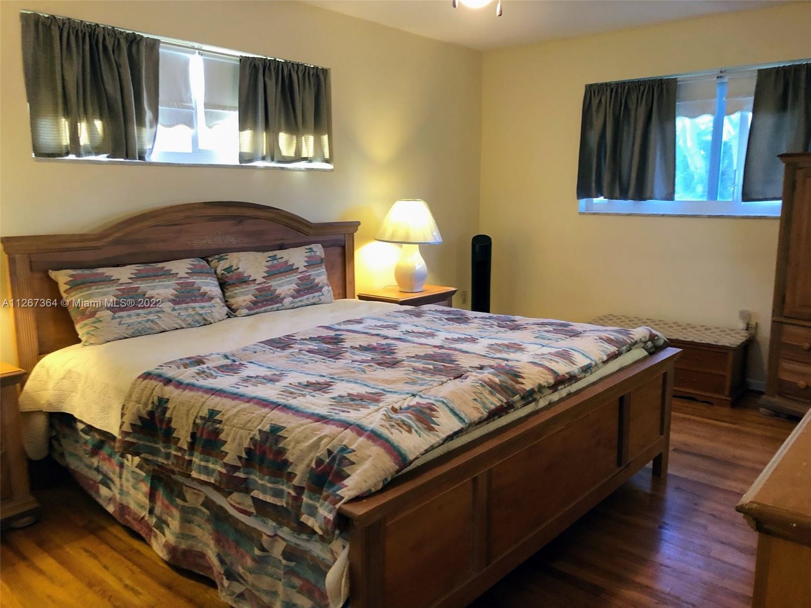 5440 Buchanan Street Hollywood, FL 33021 - Photo 27 of 34 a bedroom with a bed and a lamp with wooden floor