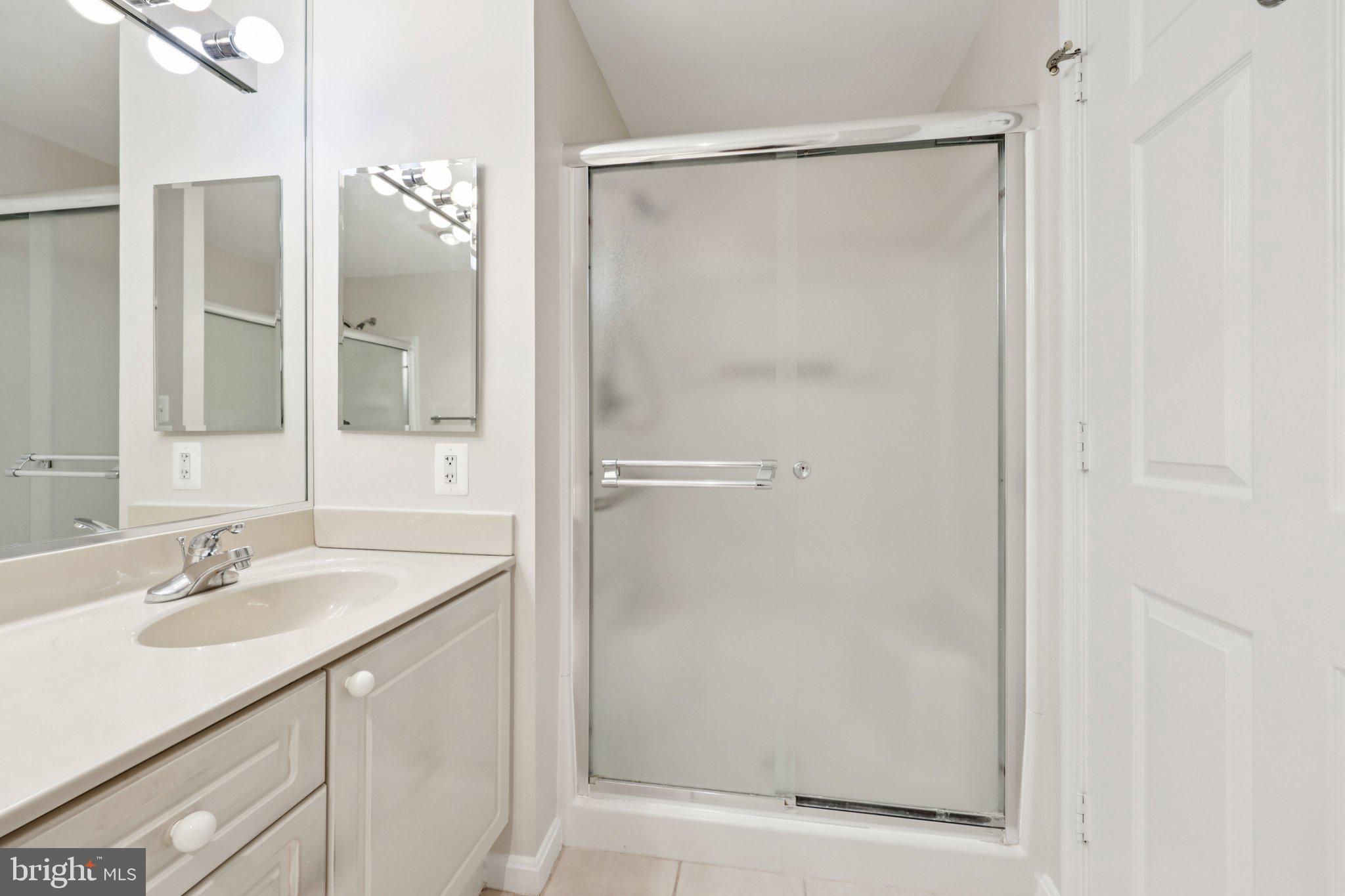 19375 Cypress Ridge Terrace, Unit 1111 Leesburg, VA 20176 - Photo 23 of 35 a bathroom with a shower sink vanity and mirror